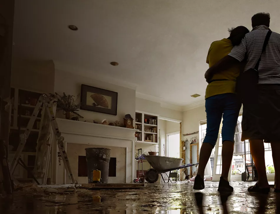 Two people standing in their water devastated home.